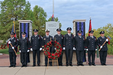 Firefighters stand in front of the Fire Department Memorial Monument.