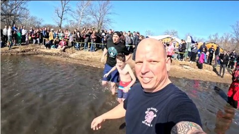 Firefighter plunges into the icy Fox River during the Law Enforcement Polar Plunge event.